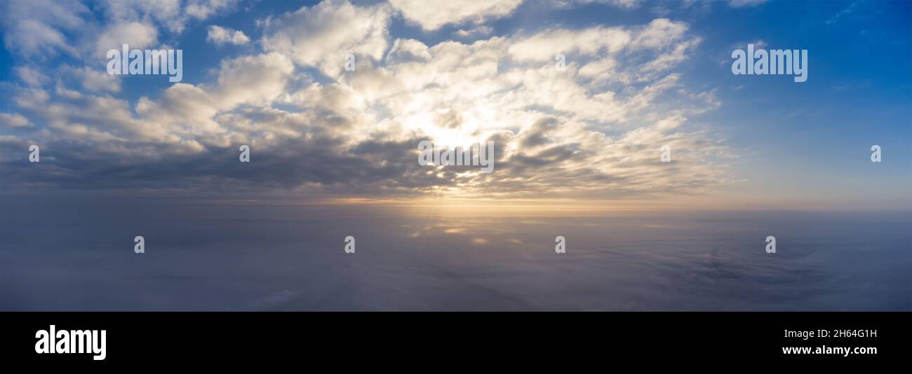 Sonnenaufgang in den Wolken über einem dichten Nebel. Panorama des Morgenhimmels, das hoch von einer Drohne geschossen wurde. Stockfoto