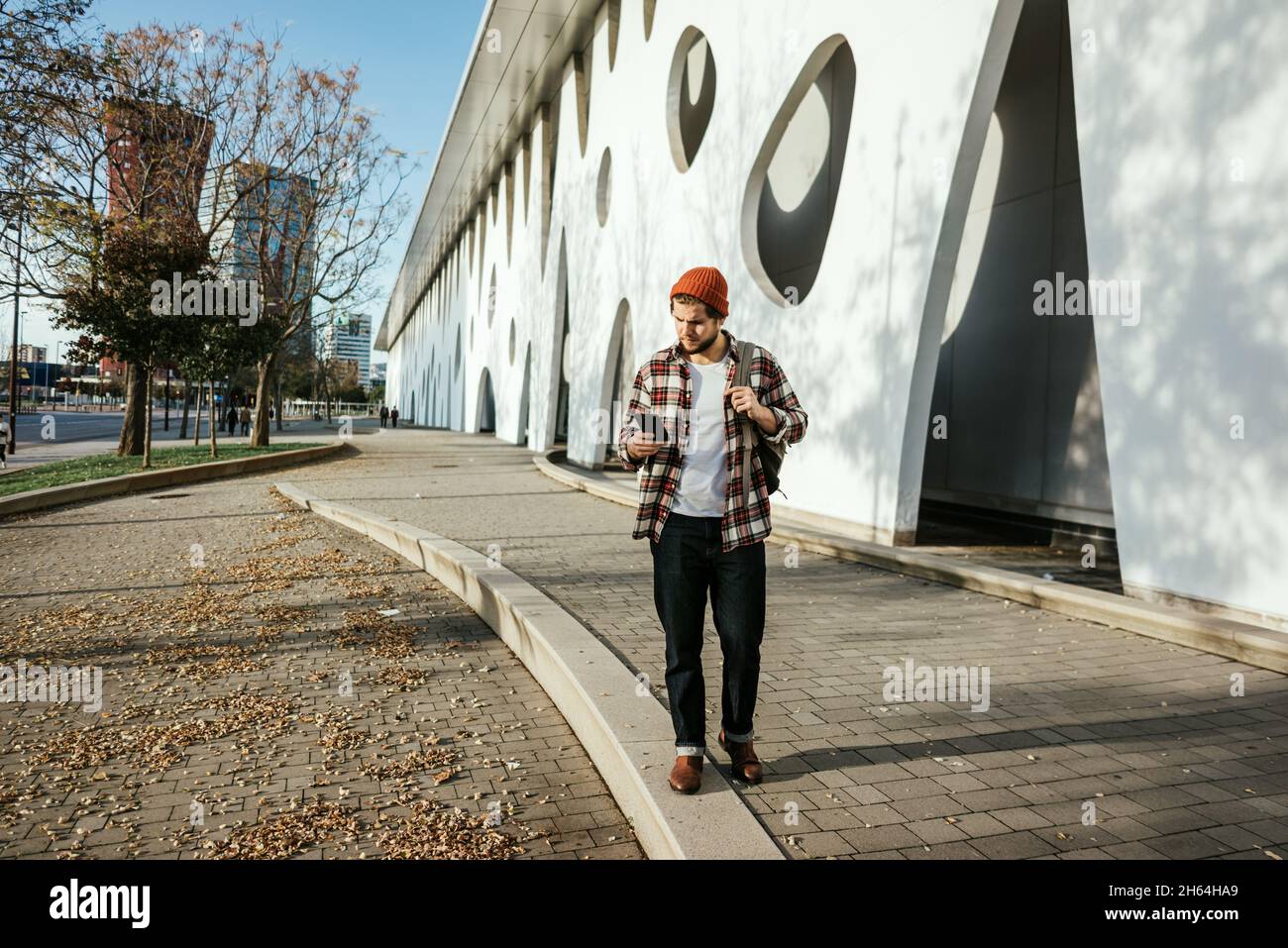 Porträt eines modernen jungen Mannes mit Smartphone auf der Straße. Hipster Kerl mit Handy in der Hand im Freien Stockfoto