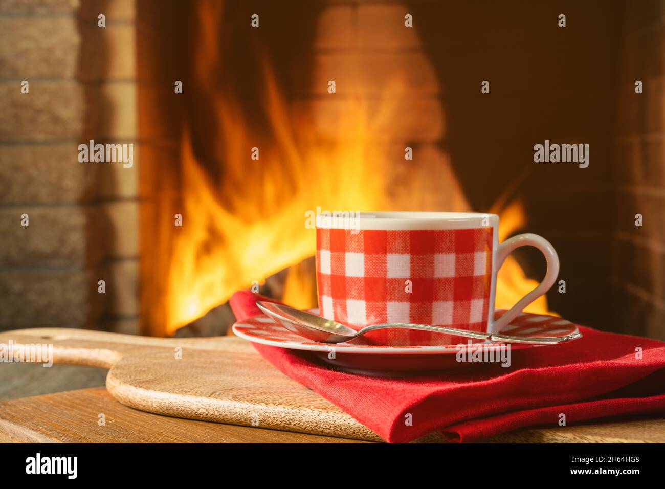 Tasse Tee oder Kaffee in der Nähe eines gemütlichen Kamins, in einem Landhaus, Herbst- oder Winterferien, horizontal. Stockfoto