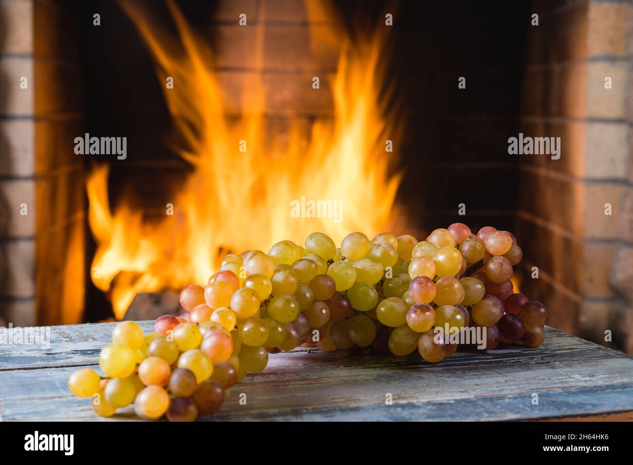 Traubenfrüchte in der Nähe eines gemütlichen Kamins, in einem Landhaus, Herbst- oder Winterferien, horizontal. Stockfoto