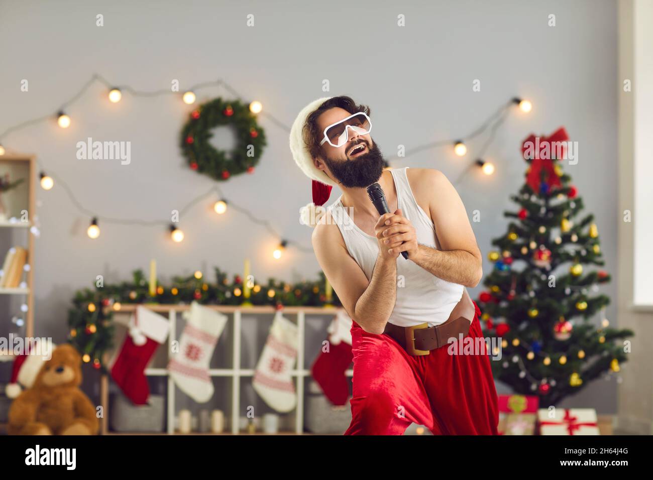 Fröhlicher, lustiger Weihnachtsmann, der im Mikrofon steht und singt Stockfoto