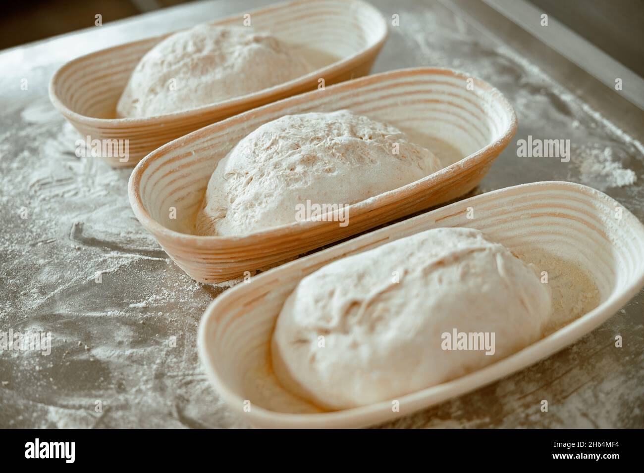 Gerichte mit rohen Brotlappen auf dem Tisch mit verstreutem Mehl in moderner Bäckerei Stockfoto