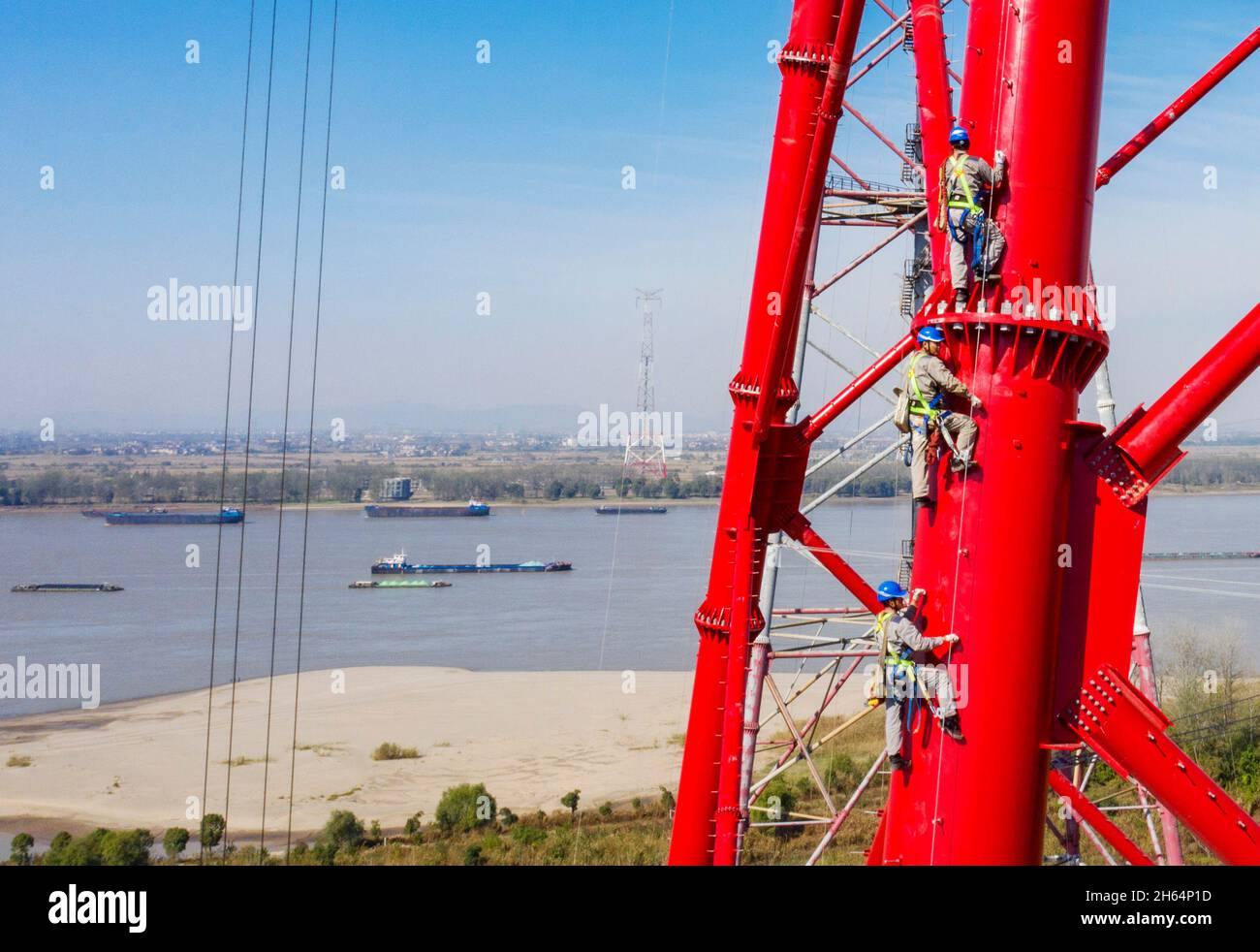 (211113) -- WUHU, 13. November 2021 (Xinhua) -- Luftfoto, aufgenommen am 11. November 2021, zeigt Arbeiter, die einen Stromübertragungsturm am Fluss Yangtze in Wuhu, der ostchinesischen Provinz Anhui, besteigen. In Wuhu, der ostchinesischen Provinz Anhui, arbeitet ein Team von Versorgungstechnikern wie "Spiermänner" entlang des Jangtse-Flusses, nietet Schrauben und baut über 100 Meter hohe Stromübertragungstürme. Die Arbeit der "Spidermänner" ist Teil des Ultra-Hochvolt-Kraftübertragungsprojekts "Baihetan-Jiangsu". Das 800-Kilovolt-Gleichstromübertragungsprojekt mit einer Gesamtlänge von 2,087 KI Stockfoto