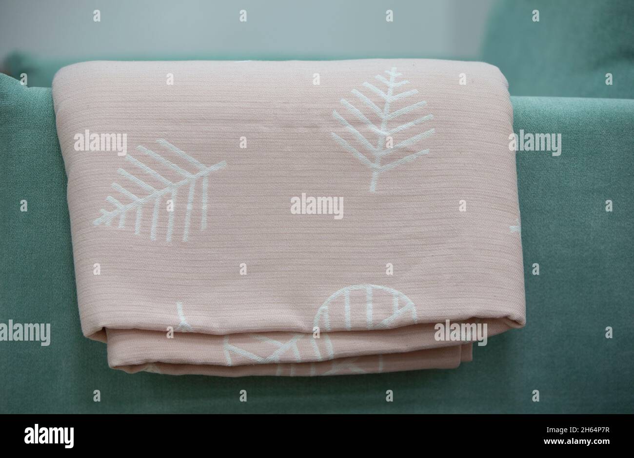 Auf der grünen Rückseite des Sofas ruht ein pinkfarbenes Coverlet mit Blumenmotiv. Stockfoto