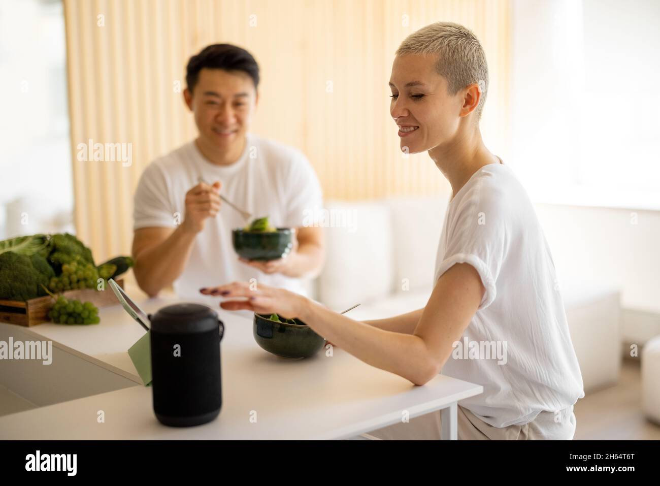 Frau verwenden tragbare Lautsprecher und essen Salat mit Mann Stockfoto