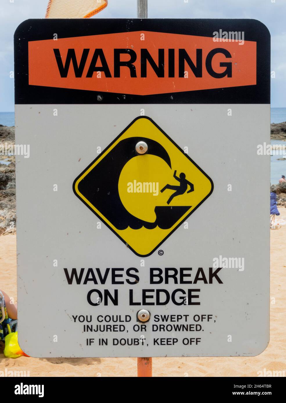 Strandschild - Warnwellen brechen auf Ledge. Stockfoto