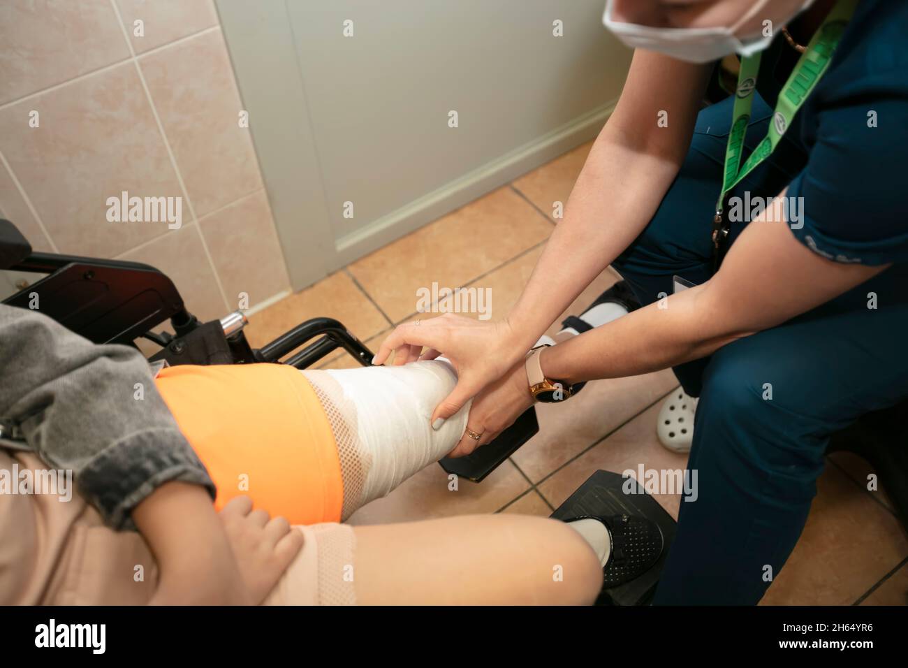Der Arzt berührt das mit einem Verband verbandte Bein. Fraktur der unteren Gliedmaßen einer Person. Behandlung von Knochenbrüchen. Es wird der Putz aufgetragen. Chirurgischer Abt Stockfoto