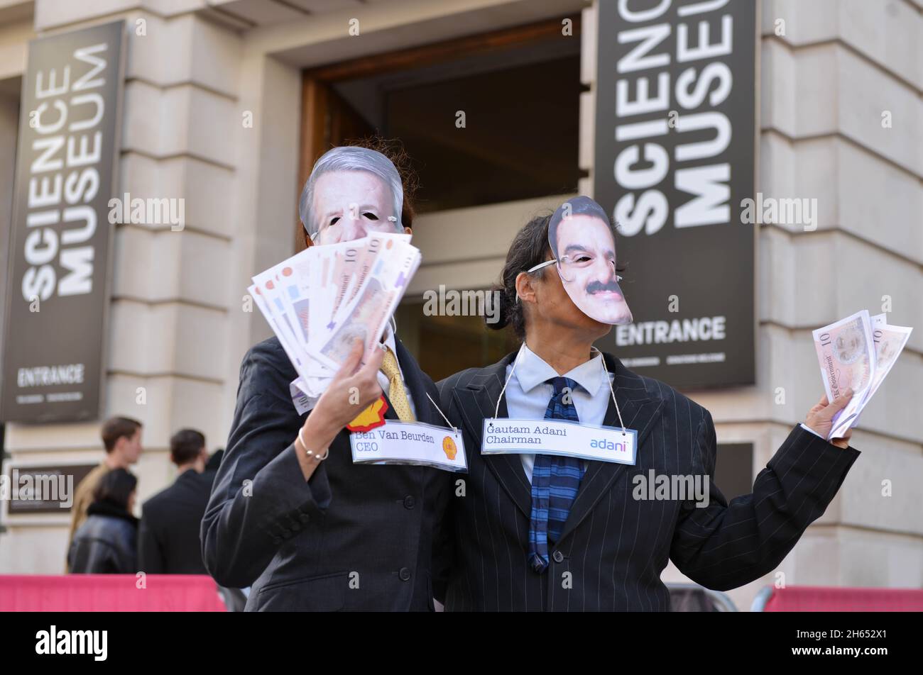 Demonstranten, die als Adani-Vorsitzender Gautam Adani und Shell-CEO Ben van Beurden gekleidet waren, posieren während der Demonstration mit gefälschtem Geld. Extinction Rebellion-Aktivisten veranstalteten einen Protest gegenüber dem Science Museum in South Kensington gegen das Sponsoring des Museums durch die fossilen Energiekonzerne Shell und Adani. Stockfoto