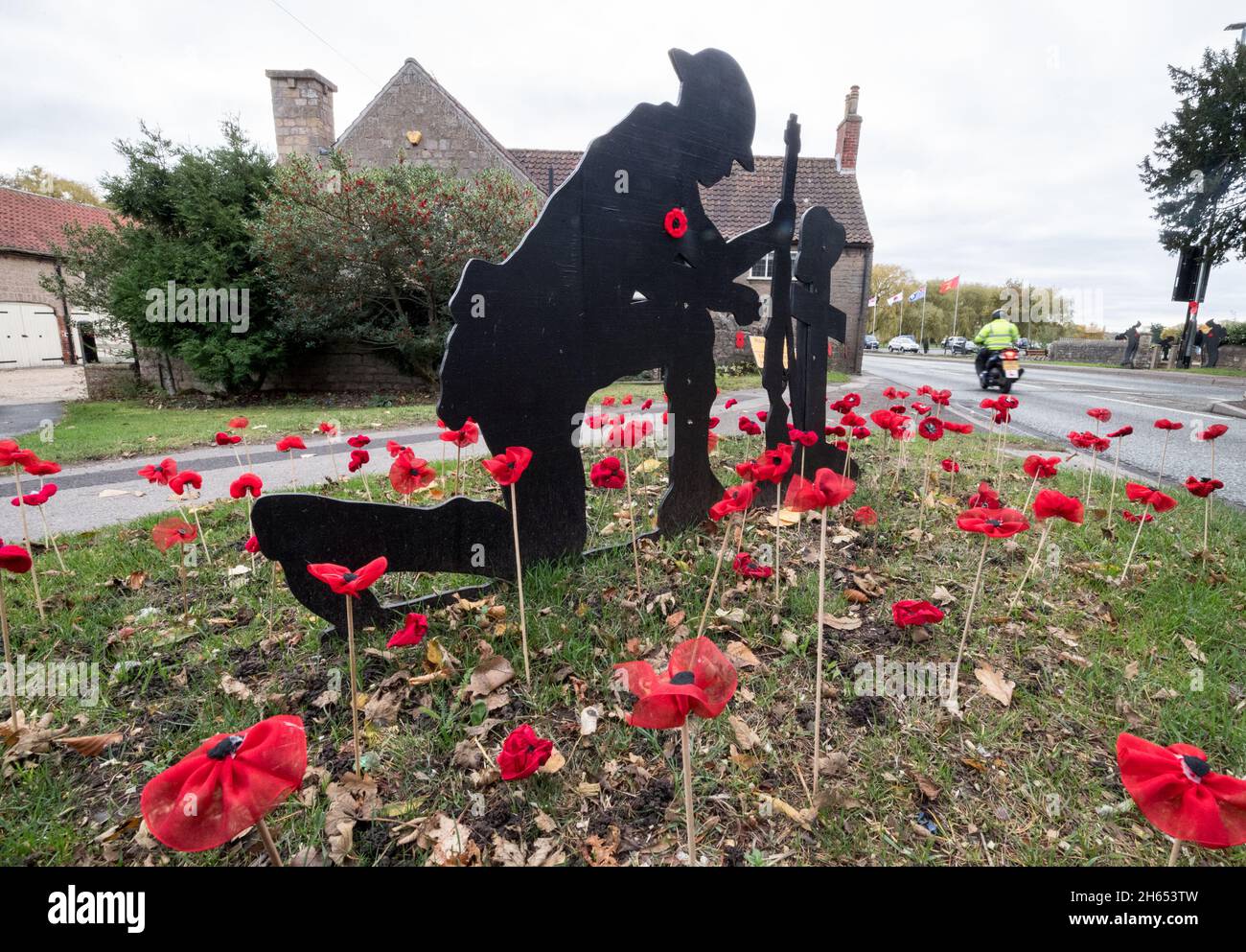 Market Warsop, Großbritannien. November 2021. Hausgemachte gestrickte rote Mohnblumen und lebensgroße Holz schwarz lackiert britischen 1.. Soldaten aus dem Weltkrieg schmücken die Hauptprozessionsroute durch die Stadt Market Warsop in Nottinghamshire zum Kriegsdenkmal der Stadt, das morgen, Sonntag, 14. November, am Gedenktag, stattfinden wird. Kredit: Alan Keith Beastall/Alamy Live Nachrichten Stockfoto