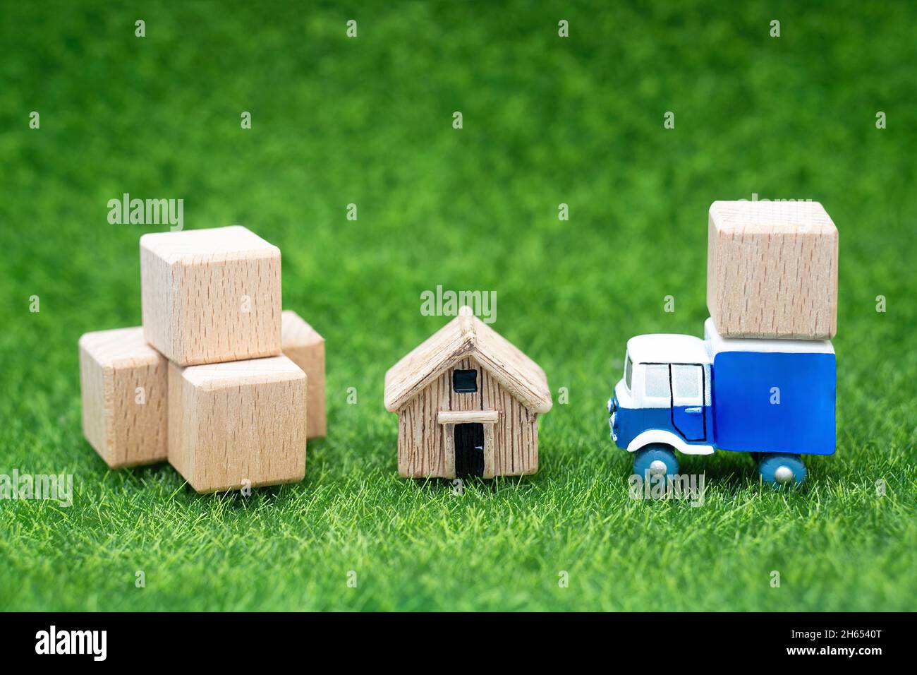 Kleines Haus, große Boxen und ein Spielzeugauto auf dem Rasen. Servicekonzept Landverlagerung. Stockfoto