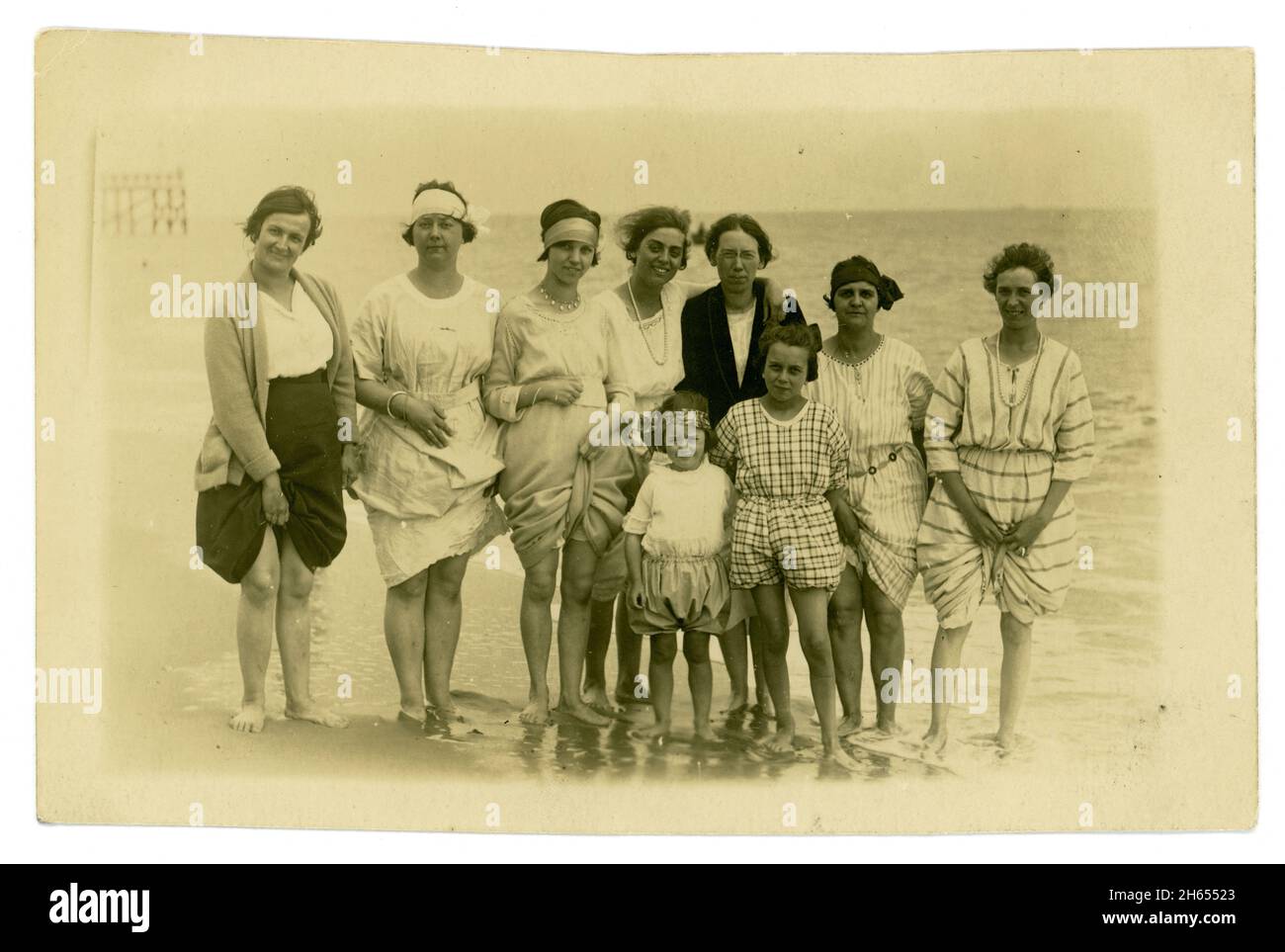 Original sehr klare Postkarte aus den 20er Jahren mit modischen Badegästen, attraktiven Frauen und Mädchen, modischen Stirnbändern und Frisuren, britischem Badeort, Pier im Hintergrund, Großbritannien Stockfoto
