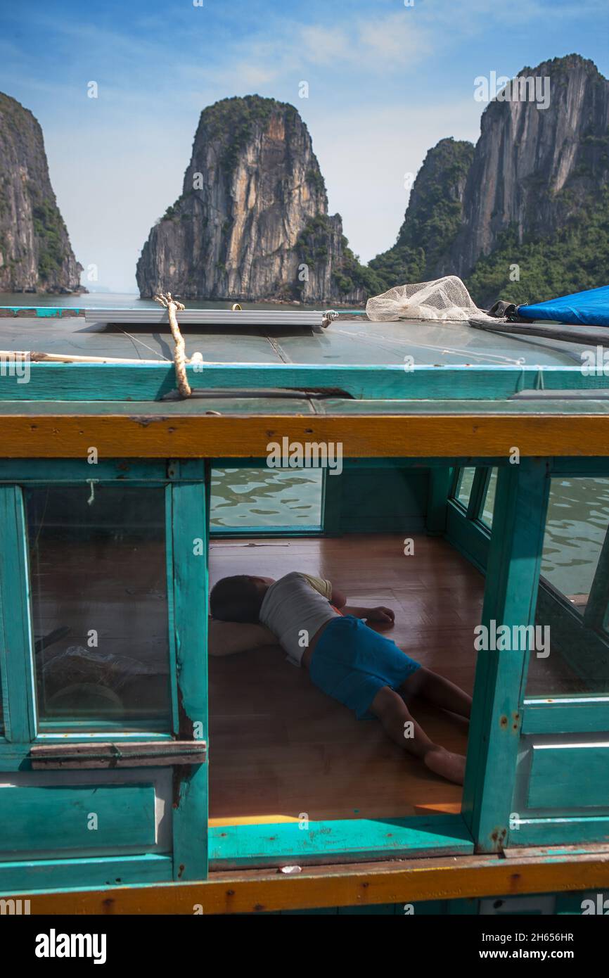 Junger Bursche schläft auf dem Boot seiner Eltern in der Ha Long Bay, Provinz Quảng Ninh, Vietnam Stockfoto