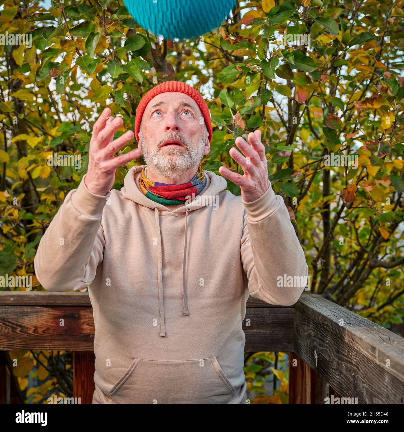 Ein älterer Mann (Ende der 60er Jahre) wirft einen schweren Slam Ball nach oben, ein Hinterhof-Workout am kalten Herbstnachmittag Stockfoto