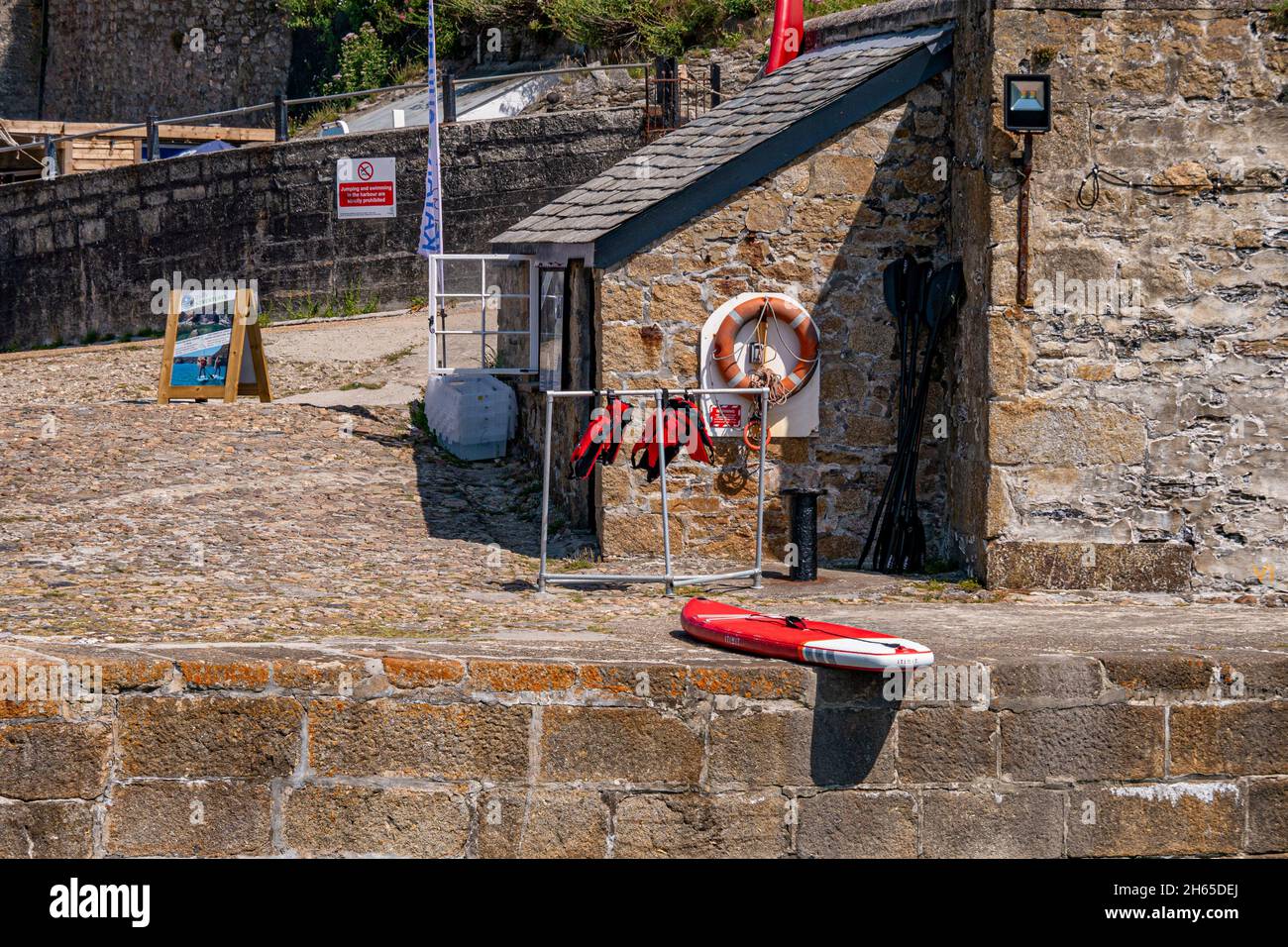 Teil des Hafens von Charlestown, wo Paddleboards von Besuchern gemietet werden können - Charlestown, Cornwall, Großbritannien. Stockfoto