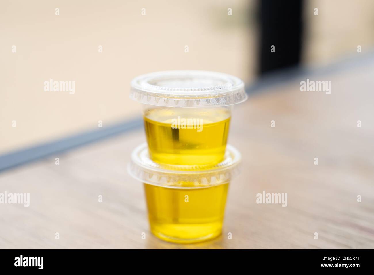 Zwei Kunststoffbehälter mit Olivenöl im Inneren. Individuelle Portion, Pandemieprotokoll-Konzept für Restaurants Stockfoto