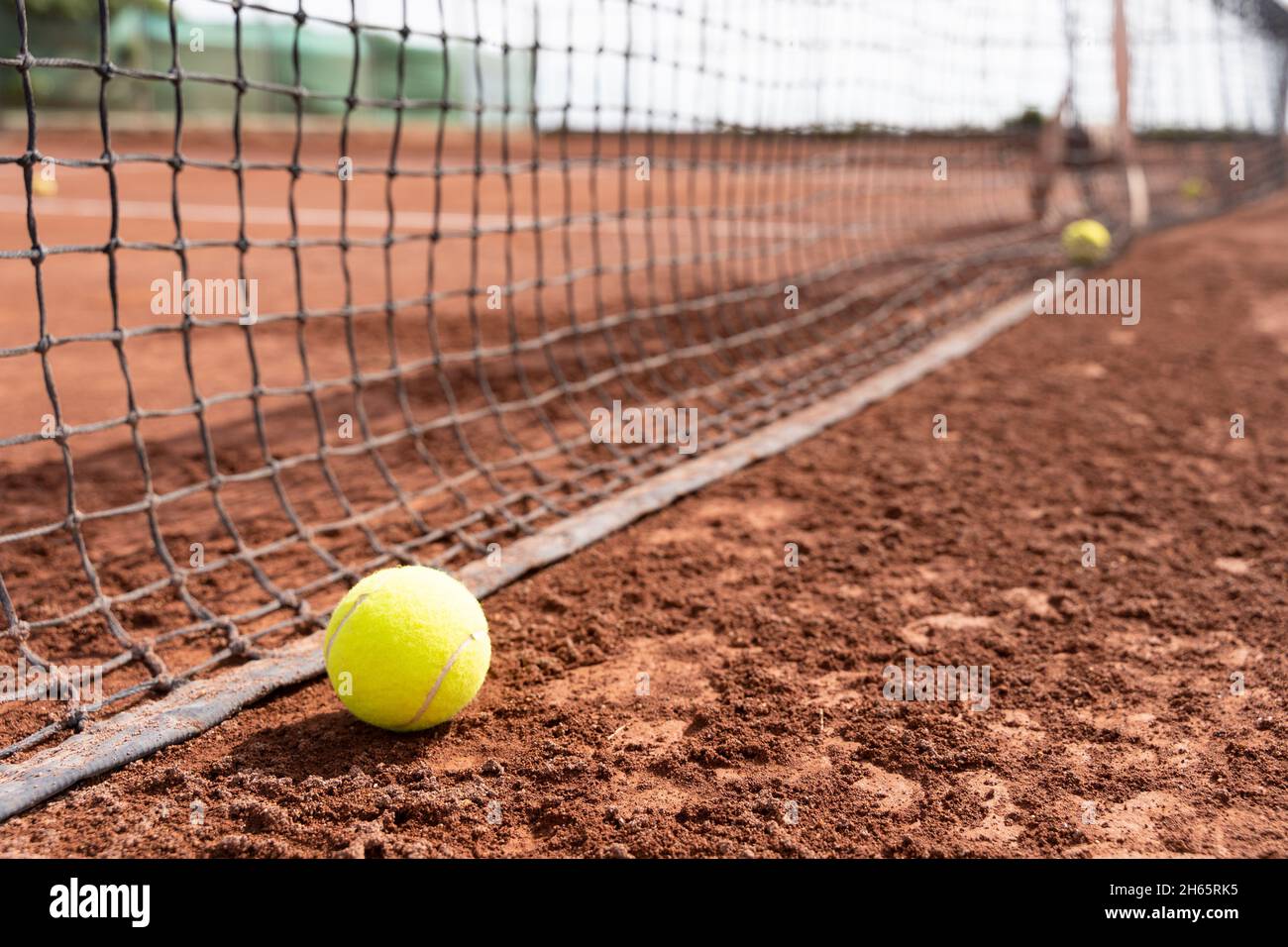 Nahaufnahme des Tennisballs auf dem nassen Sandplatz in der Nähe des Netzes. Sporttraining, Turnierkonzepte Stockfoto