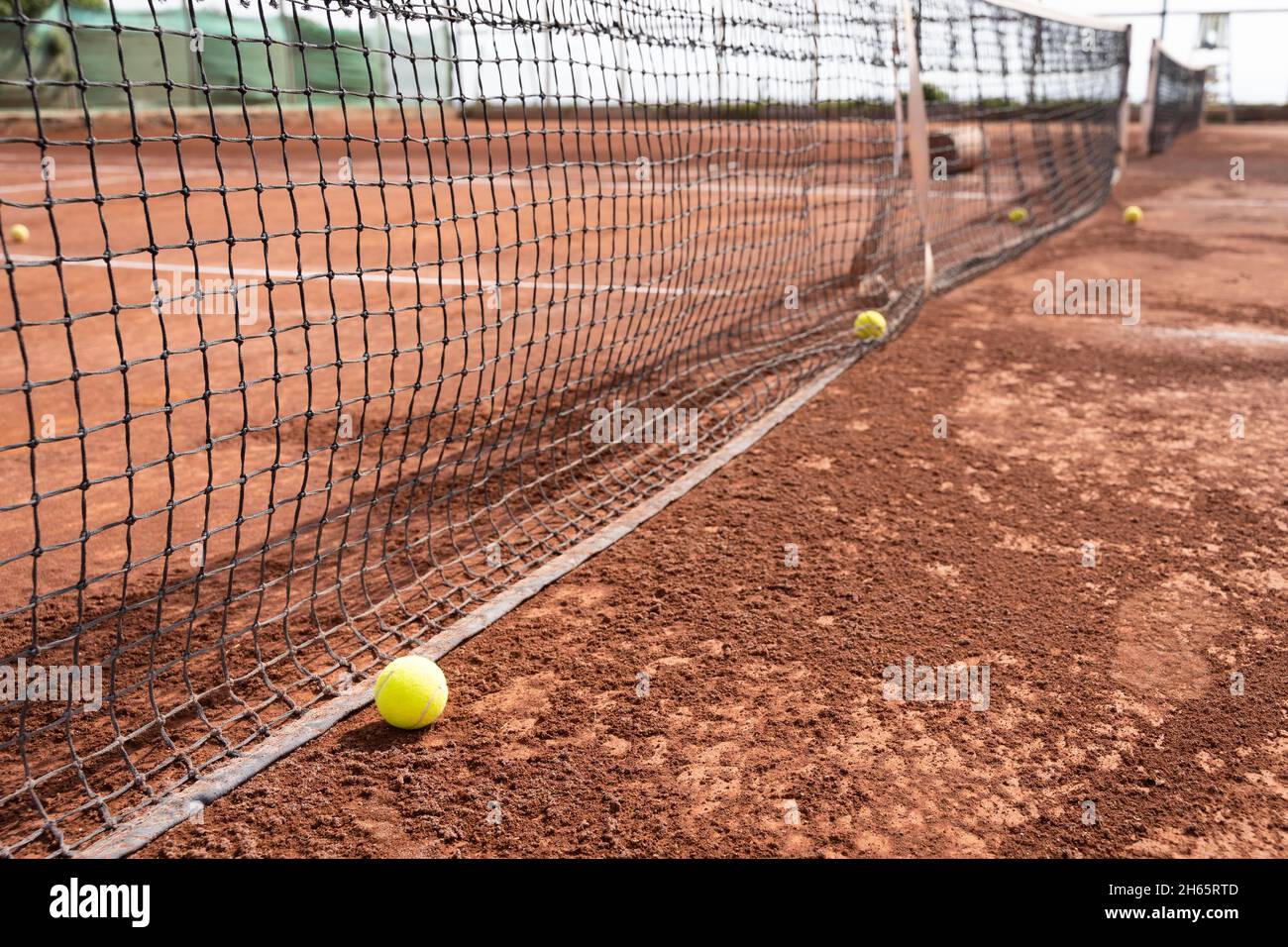 Tennisbälle im Netz auf dem Sandplatz. Sportturnier, Trainingskonzepte Stockfoto