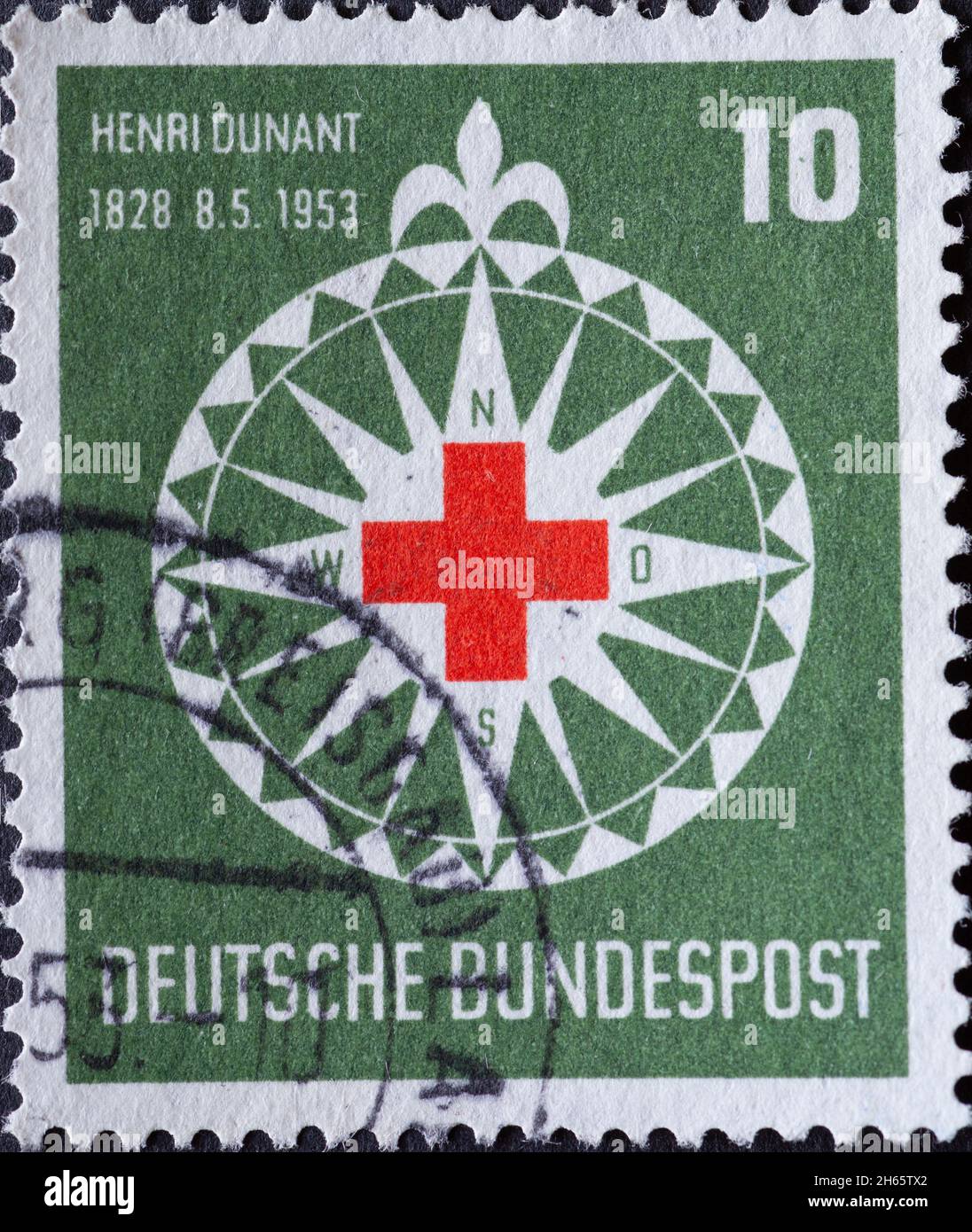 DEUTSCHLAND - UM 1953:auf dieser in Deutschland gedruckten Briefmarke sehen Sie das Symbol des Roten Kreuzes in einer stilisierten Windrose. Der Hintergrund ist grün Stockfoto