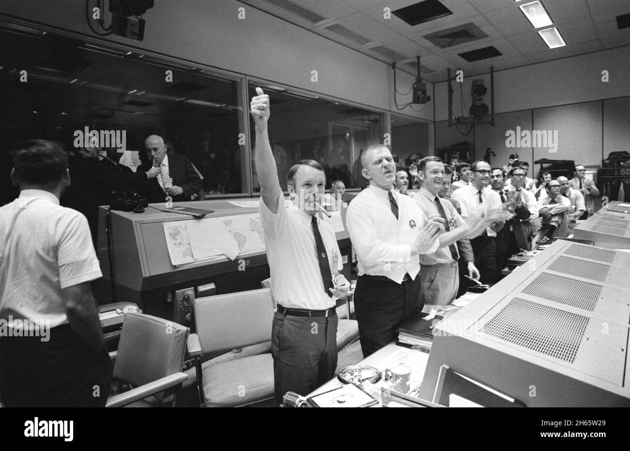 Drei der vier Apollo 13-Flugdirektoren applaudieren dem erfolgreichen Abplatschen des Kommandomoduls „Odyssey“, während Dr. Robert R. Gilruth, Direktor des Manned Spacecraft Center (MSC), und Dr. Christopher C. Kraft Jr., stellvertretender Direktor des MSC, Zigarren anzünden (oben links). Die Flight Directors sind von links nach rechts: Gerald D. Griffin, Eugene F. Kranz und Glynn S. Lunney. Stockfoto