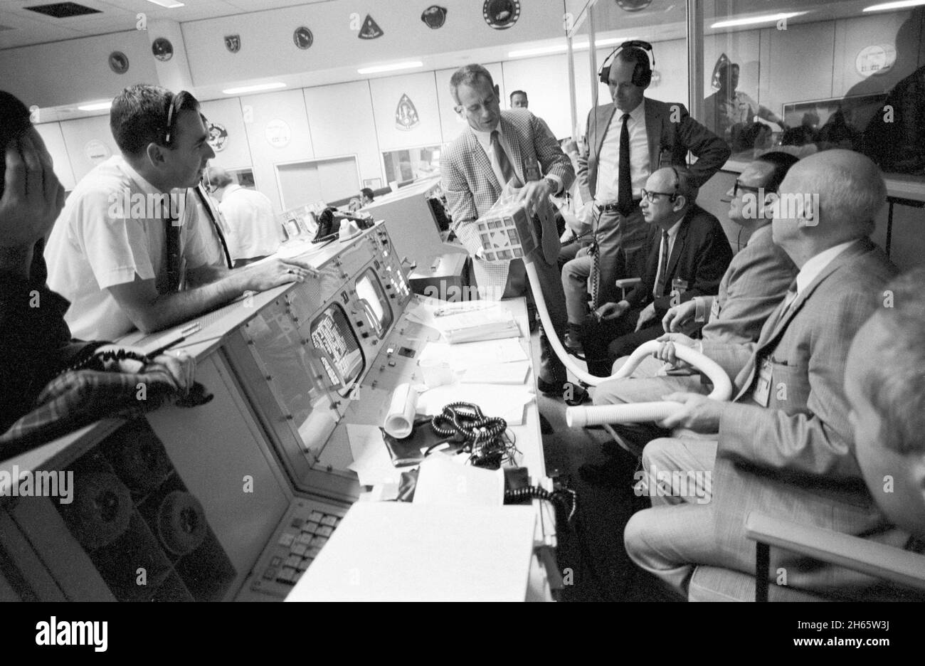 Deke Slayton (karierte Jacke) zeigt den Adapter, der für die Verwendung von quadratischen Lithium-Hydroxid-Kanistern des Command Module entwickelt wurde, um überschüssiges Kohlendioxid aus der Apollo 13 LM-Kabine zu entfernen. Der Adapter wurde von Ed Smylie entwickelt. Von links nach rechts sind Mitglieder des Publikums von Slayton Flugdirektor Milton L. Windler, stellvertretender Direktor/Flugbetrieb Howard W. Tindall, Direktor/Flugbetrieb Sigurd A Sjoberg, stellvertretender Direktor/bemanntes Raumflugzentrum Christopher C. Kraft und Direktor/bemanntes Raumflugzentrum Robert R. Gilruth. Stockfoto