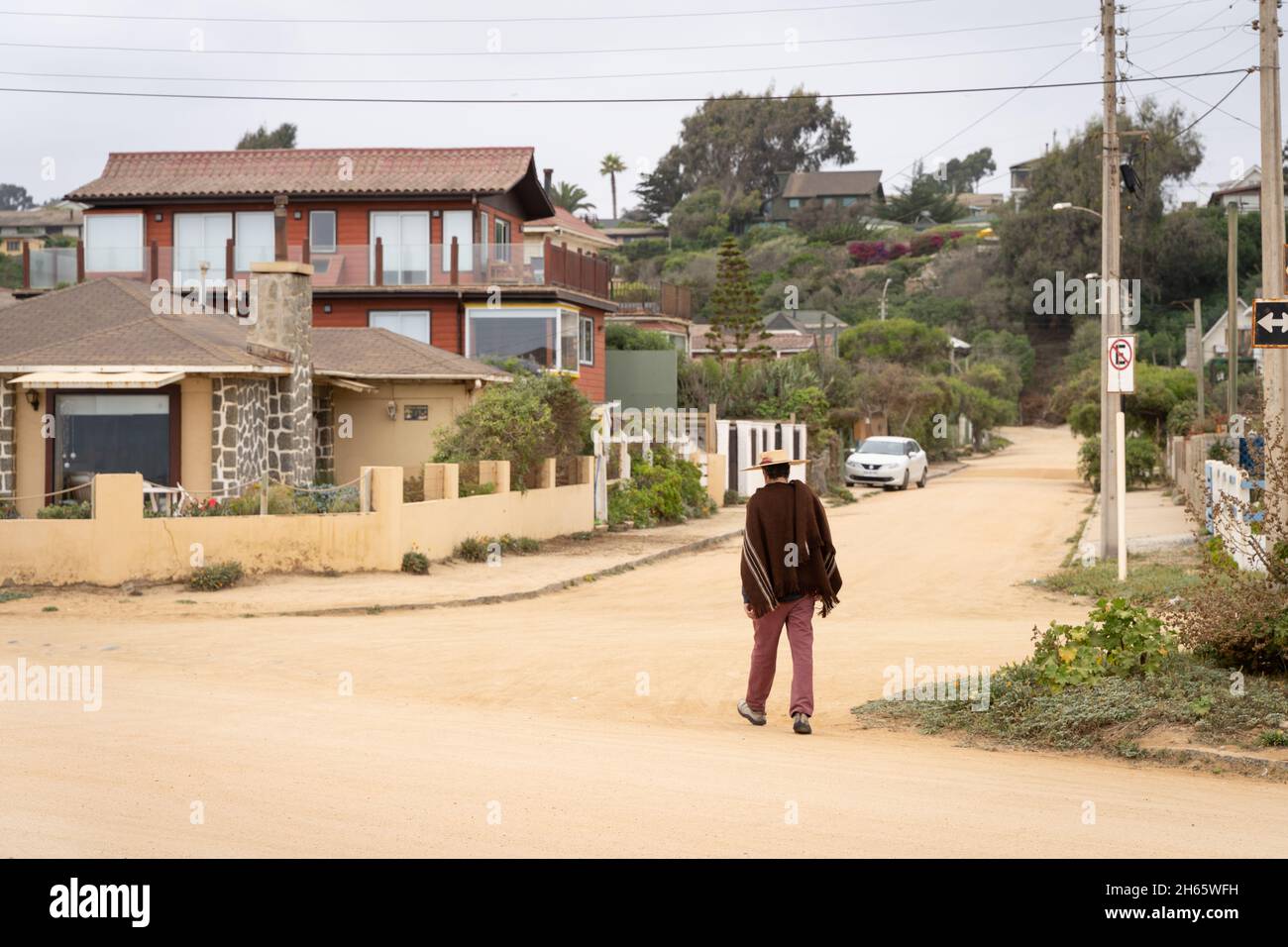 Einsamer Bauer, der während der Pandemie von Covid-19 in Algarrobo, Chile, auf einer leeren, unbefestigten Straße unterwegs ist Stockfoto