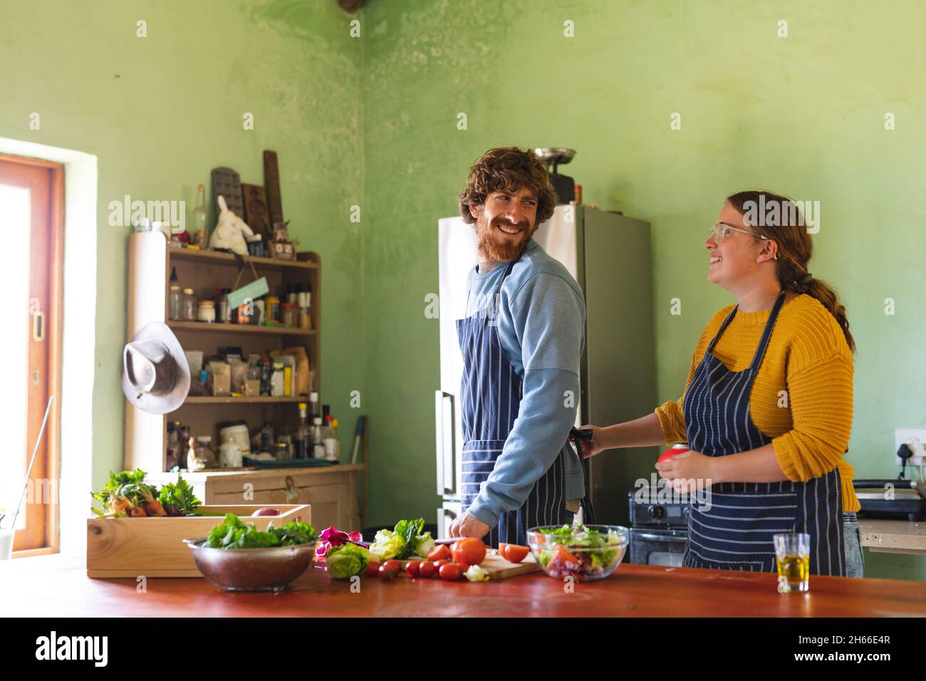 Glückliches junges Paar, das Freizeit zusammen verbringt, während es in der Küche zu Hause kocht Stockfoto