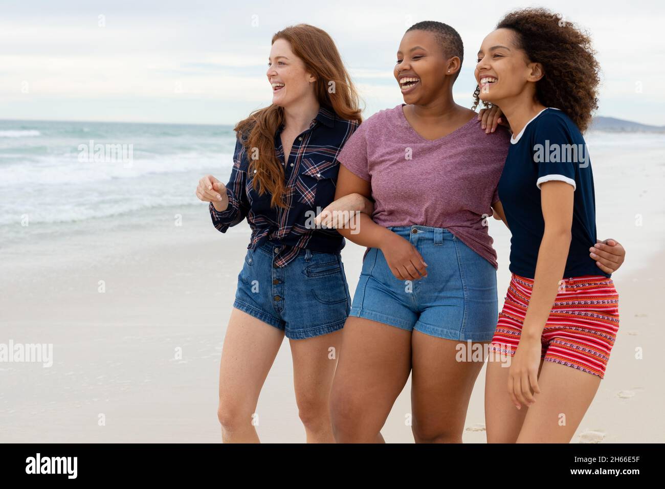 Fröhliche, multirassische junge Freundinnen in Casuals, die ein gemeinsames Wochenende am Strand genießen Stockfoto