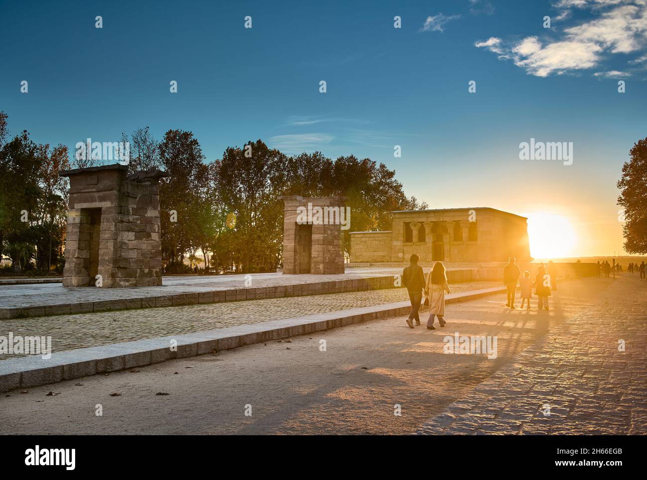 Menschen, die bei Sonnenuntergang den Cuartel de la Montana Park mit dem Tempel von Debod im Hintergrund überqueren. Madrid, Spanien. Stockfoto