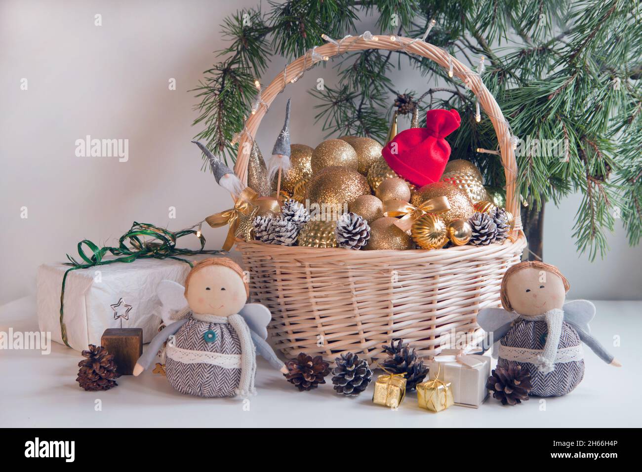 Korbkorb gefüllt mit goldenen Kugeln, Geschenken, Spielzeug und Tannenzapfen, um Weihnachtstanne zu schmücken Stockfoto