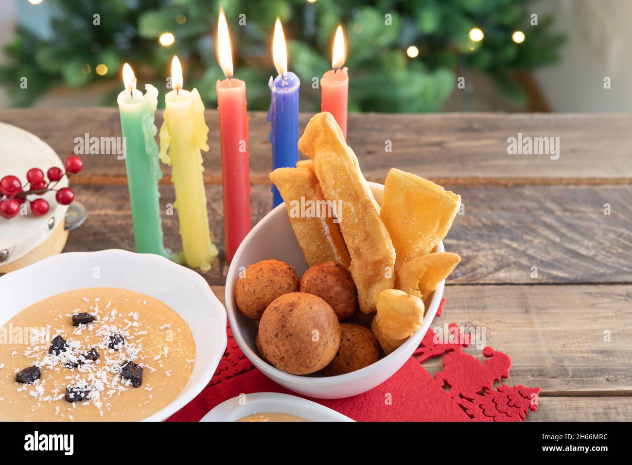 Tag Bei Kerzenschein. Typisch kolumbianisches Essen. Buñuelo, Pudding und Flocken mit Kerzen und Weihnachtsbaum im Hintergrund. Traditioneller kolumbianischer Urlaub. Stockfoto