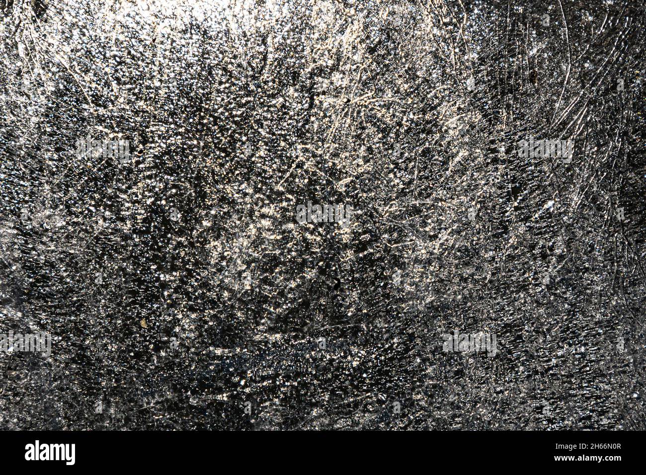 Transparente Eisoberfläche mit Struktur und Muster. Frostiger Hintergrund. Vereisung und Kühlwirkung. Kühle und winterliche Kulisse. Stockfoto