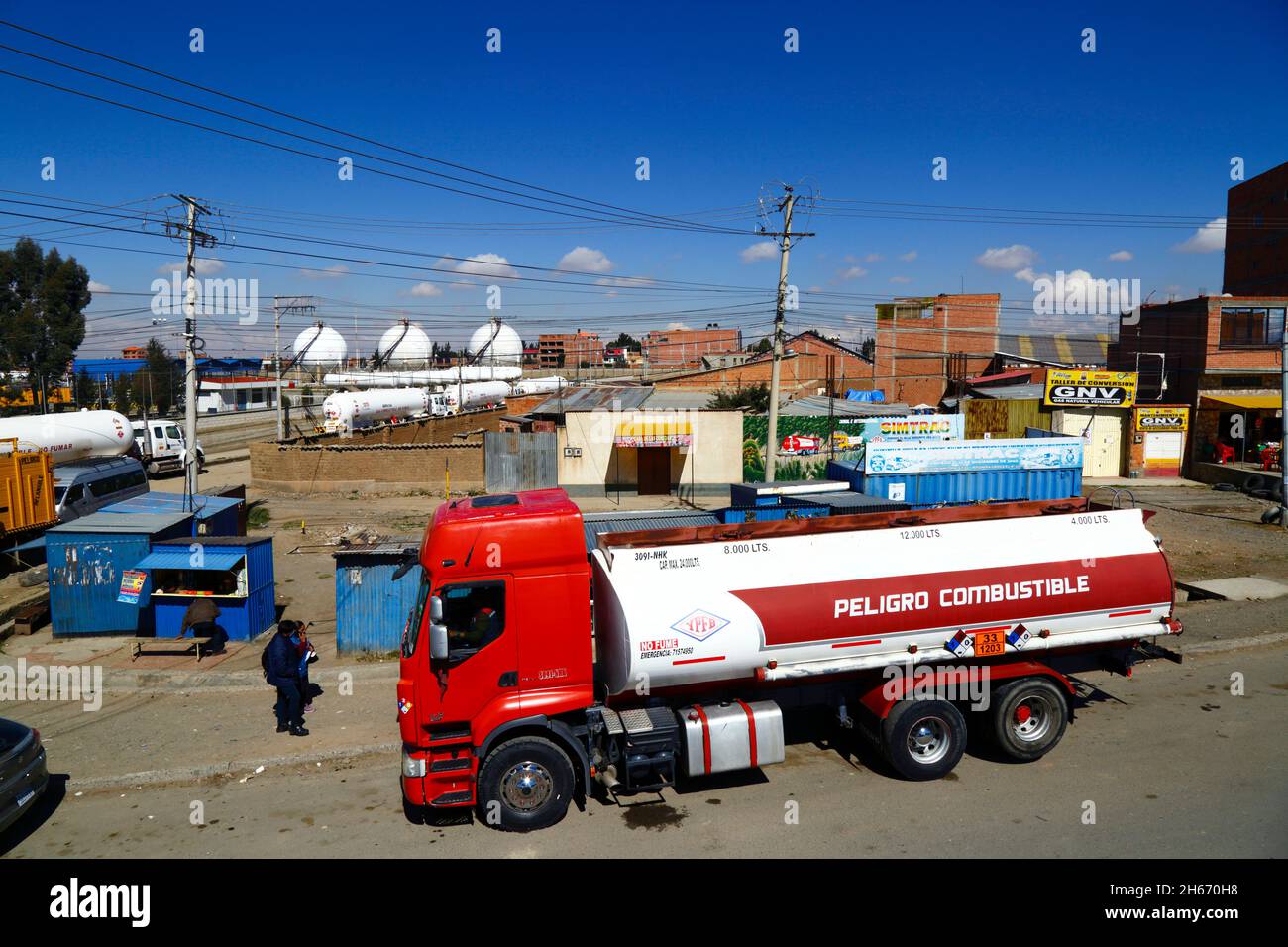 Senkata, El Alto, Bolivien. November 2021. Ein Tankwagen wartet vor der Senkata-Treibstofffabrik auf der Av 6 de Marzo / Camino Oruro in El Alto. Yacimientos Petrolíferos Fiscales Bolivianos (YPFB, Boliviens staatliches Öl- und Gasunternehmen) verfügt hier über eine große Raffinerie- und Speicheranlage, die La Paz beliefert; El Alto und Umgebung mit Benzin, Diesel und flüssigem Erdgas (in Flaschen für den Hausgebrauch und auch für Fahrzeuge und andere Industrien). Im Hintergrund sind einige Flüssiggas-Tankwagen und sphärische Gasspeichertanks zu sehen. Stockfoto