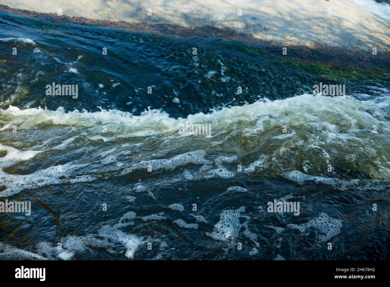 Abstrakter Hintergrund. Die Wellen des Süßwassers treffen sich mit den spitzen Unterwasserfelsen, die Whirlpools bilden. Whirlpools in der Region des einzigen Steppenwaterfals Stockfoto