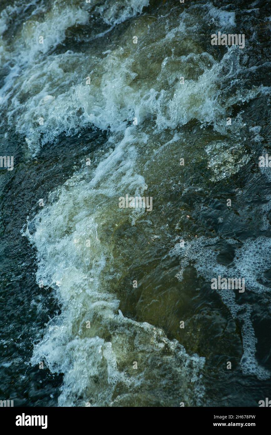 Abstrakter Hintergrund. Die Wellen des Süßwassers treffen sich mit den spitzen Unterwasserfelsen, die Whirlpools bilden. Whirlpools in der Region des einzigen Steppenwaterfals Stockfoto