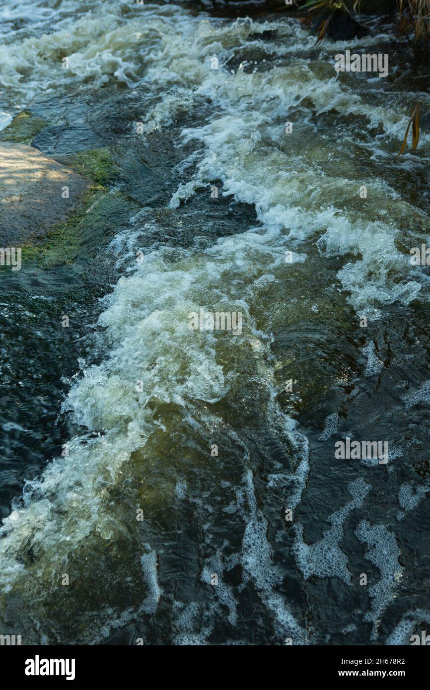 Abstrakter Hintergrund. Die Wellen des Süßwassers treffen sich mit den spitzen Unterwasserfelsen, die Whirlpools bilden. Whirlpools in der Region des einzigen Steppenwaterfals Stockfoto