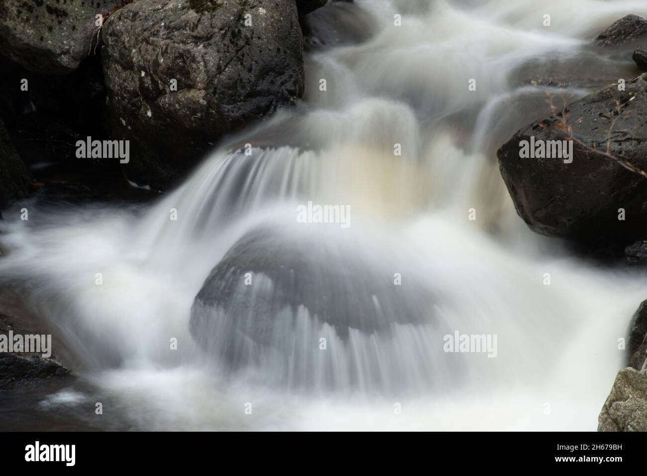 Nahaufnahme eines Wasserfalls mit Wasser, das über Felsbrocken rauscht, Großbritannien Stockfoto