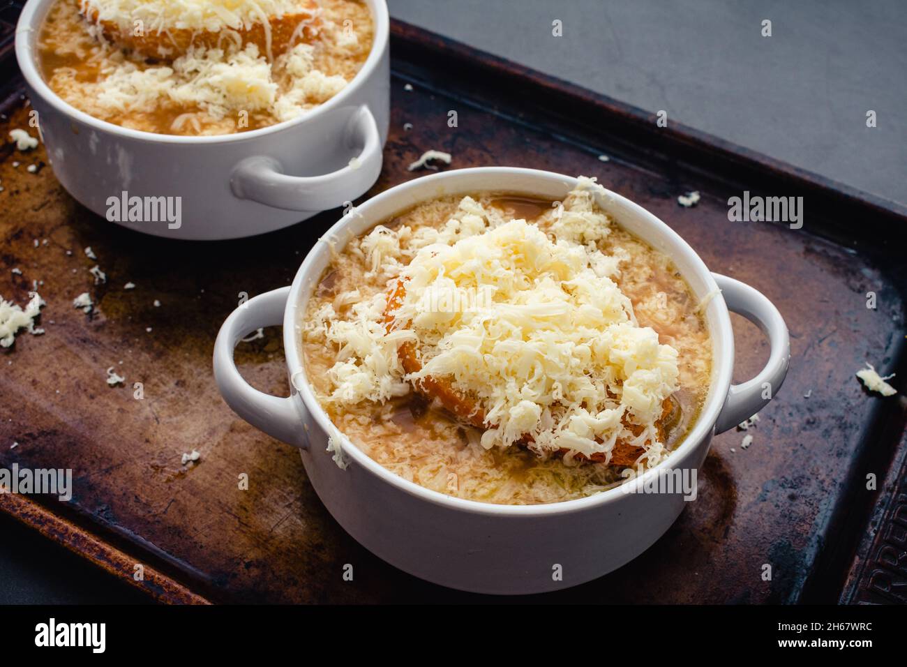 Schüsseln mit französischer Zwiebelsuppe mit geröstetem Brot und geriebenem Käse: Schüsseln mit französischer Zwiebelsuppe auf einer Pfanne Stockfoto