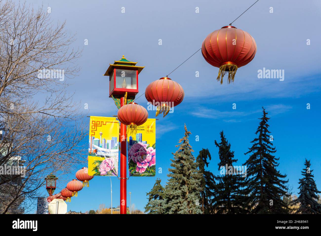 Calgary, Kanada - 13. November 2021: In der Innenstadt von Chinatown in Calgary hängen rote Laternen an chinesischen Straßenlaternen mit bunten Bannern. Stockfoto