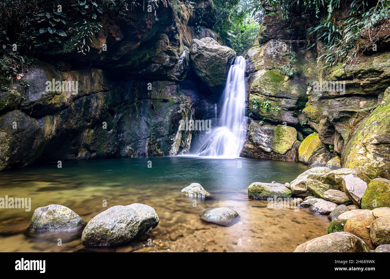 Schöner Wasserfall mit klarem Wasser, der zwischen Felsformationen und grüner Vegetation fließt und die Serra do Mar verschönert Stockfoto