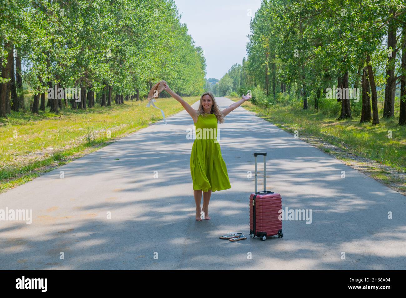 Ein junges Mädchen in einem grünen Kleid steht auf einer schmalen Straße Stockfoto