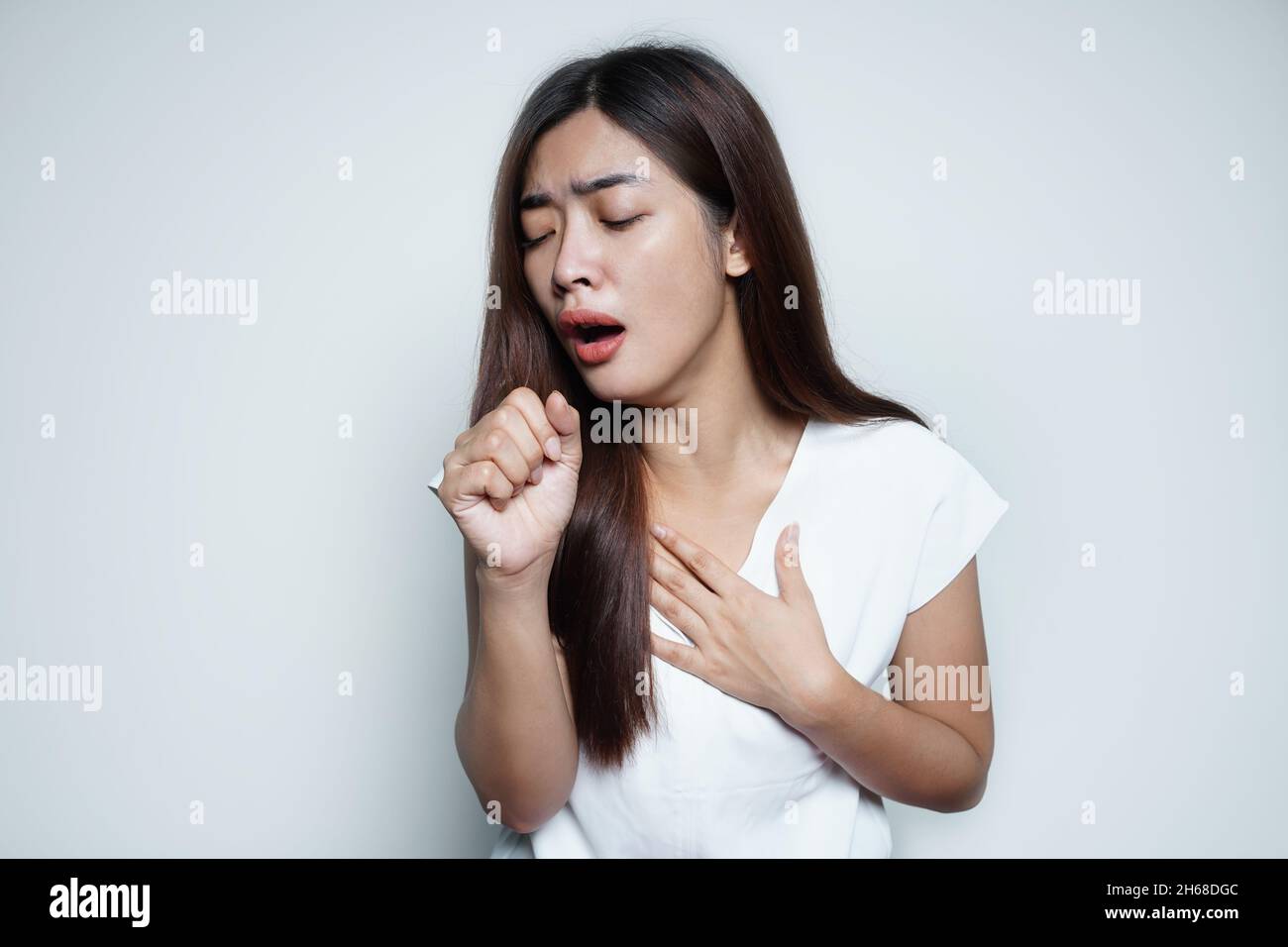 Eine kranke Frau hustet und hält ihre schmerzende Brust Stockfoto