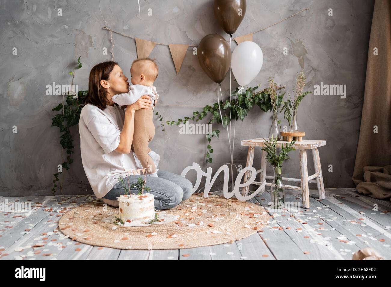 Erster Geburtstag von Kleinkind Junge, Kind und Mutter in rustikalen minimalistischen Dekoration, neutralen Hintergrund. Ort für Ihren Text. Stockfoto