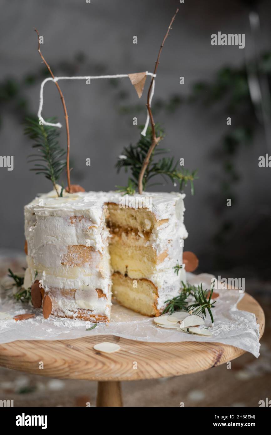 Rustikale Geburtstagstorte, Seitenschnitt, weiße Kuchen mit Buttercreme, Wandhintergrund, Biskuitkuchen. Dekorierter Hochzeitstorte. Hausgemachte Kuchen auf einem Tisch Stockfoto Rustikale Geburtstagstorte, Seitenschnitt, weiße Kuchen mit Buttercreme, Wandhintergrund, Biskuitkuchen. Dekorierter Hochzeitstorte. Hausgemachte Kuchen auf einem Tisch Stockfoto