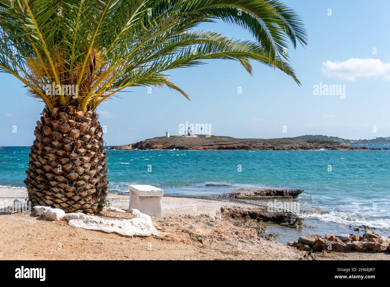 Griechische Ägäis mit einer Palme und einer kleinen Insel mit einer orthodoxen Kirche. Schönes landschaftlich schönes Reiseziel in Südeuropa. Stockfoto