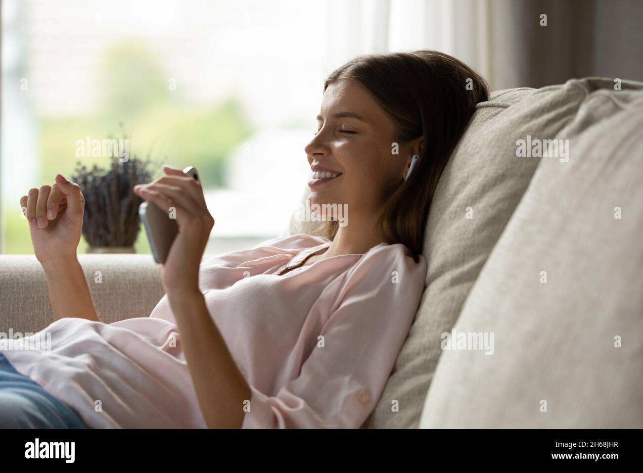 Entspannte, sorglose Millennial-Frau, die Musik in Kopfhörern hört. Stockfoto