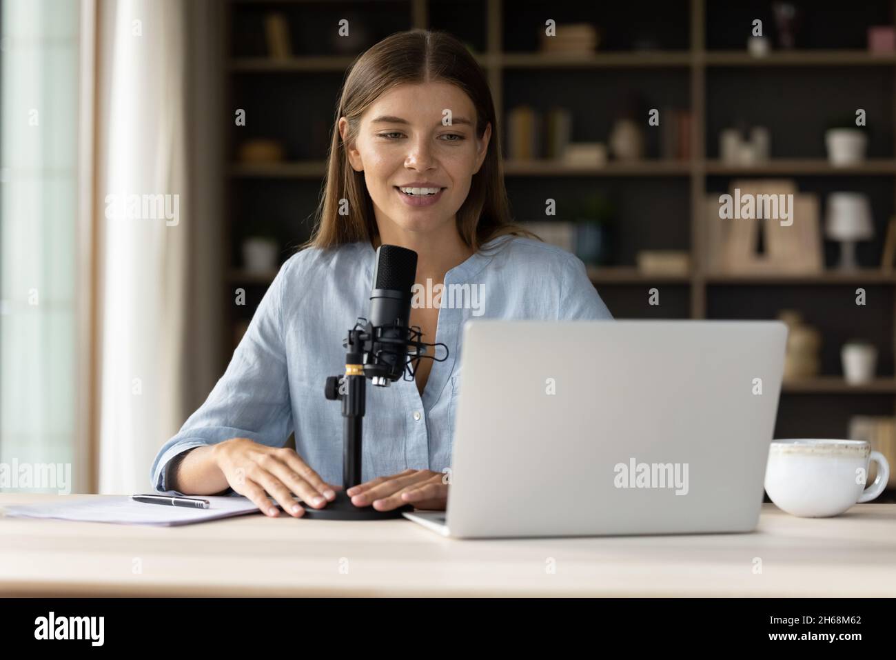 Glücklich attraktive junge professionelle Bloggerin im Standmikrofon reden. Stockfoto