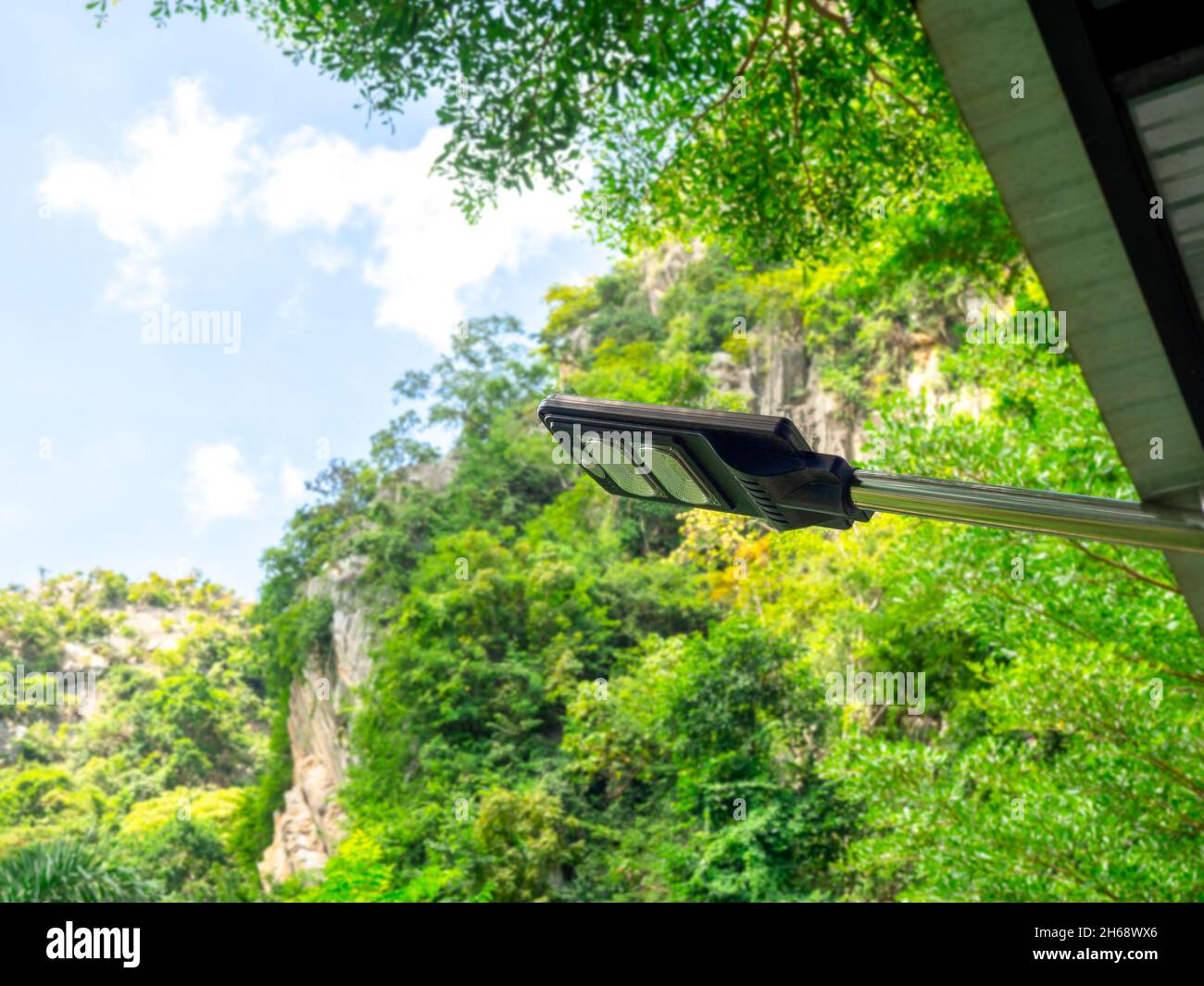 Solarleuchte. Moderne elektrische Leistung führte Glühbirne hängen auf der Stange unter dem Dach des Gebäudes auf grünen Natur Berg und blauen Himmel Hintergrund. Stockfoto