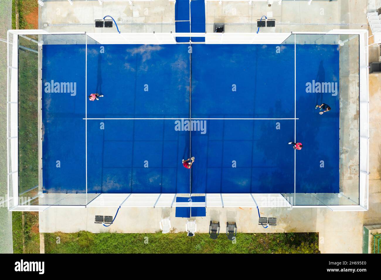 Blick von oben, atemberaubende Luftaufnahme von einigen Menschen, die auf einem blauen Padel-Platz spielen. Stockfoto
