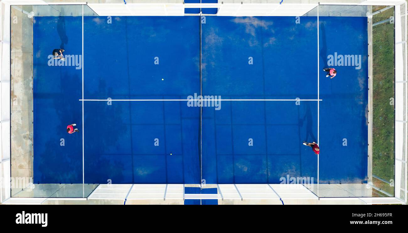 Blick von oben, atemberaubende Luftaufnahme von einigen Menschen, die auf einem blauen Padel-Platz spielen. Stockfoto