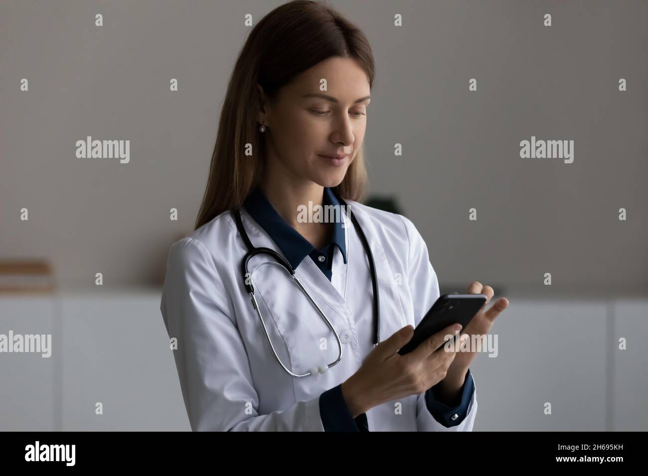 Kopfschuss selbstbewusste weibliche Ärztin in Uniform mit Smartphone Stockfoto